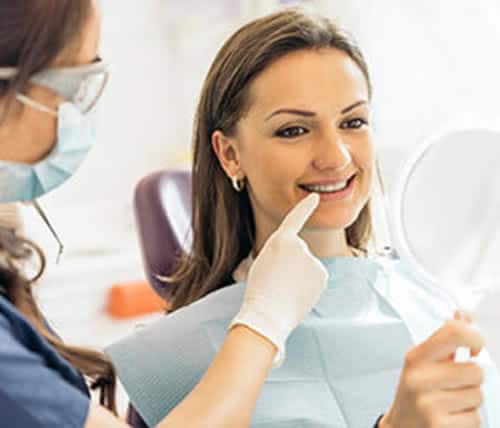 A Patient Seeing Her Teeth In Mirror After Treatment